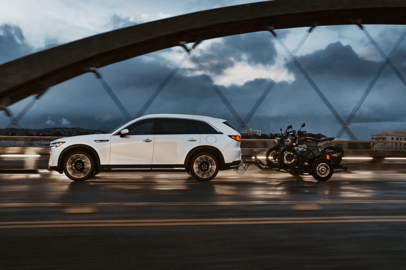 Vue latérale du Mazda CX-90 PHEV 2025 remorquant deux motos.