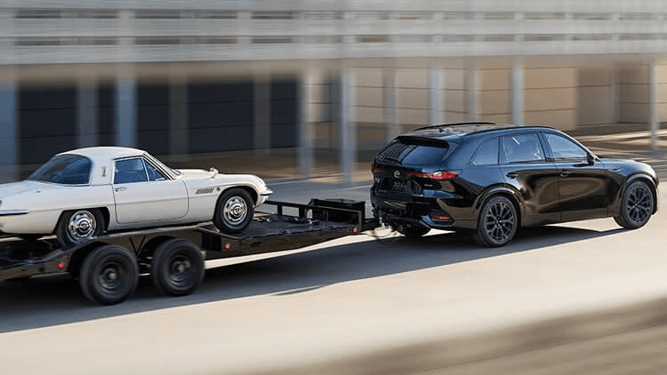 Le Mazda CX70 Hybride 2025 qui remorque une voiture sur une remorque.